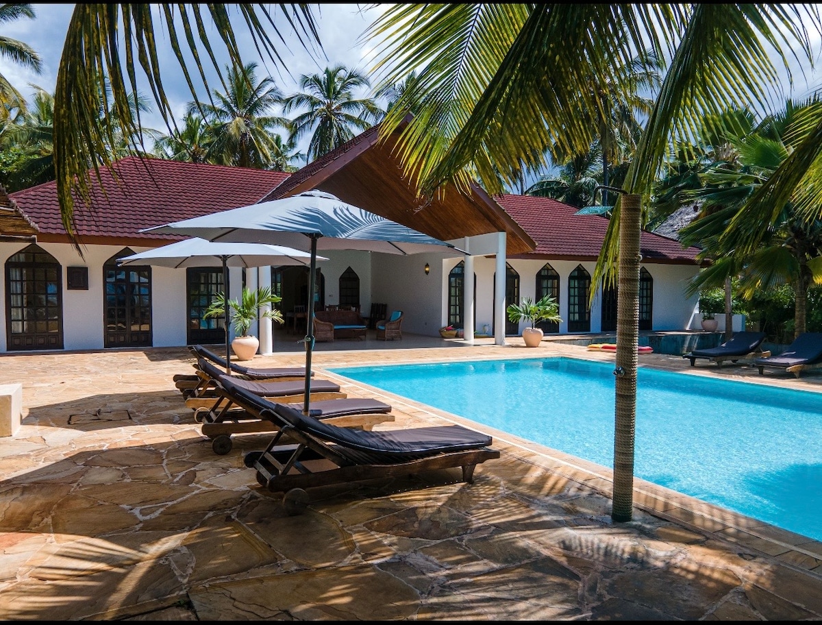 Pool terrace with sun loungers, stone paving and villa facade
